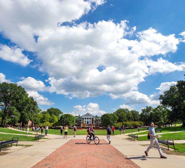 A wide shot of students walking across the Mall, view of Main Administration Building in the background.